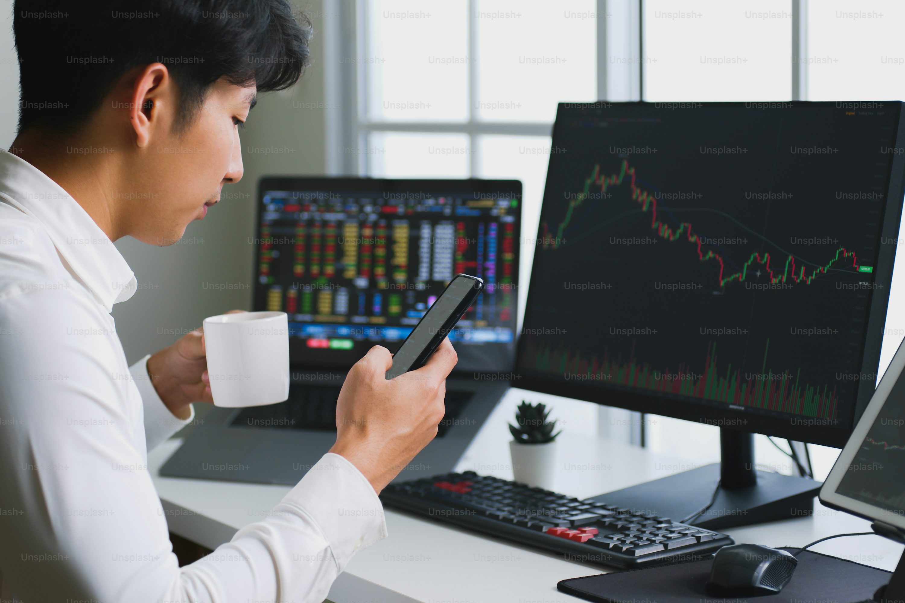 Young American investors using laptops and smartphones to analyze cryptocurrency trends in a modern workspace, reflecting 2025 investment habits.